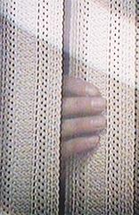 A hand pushes aside a curtain